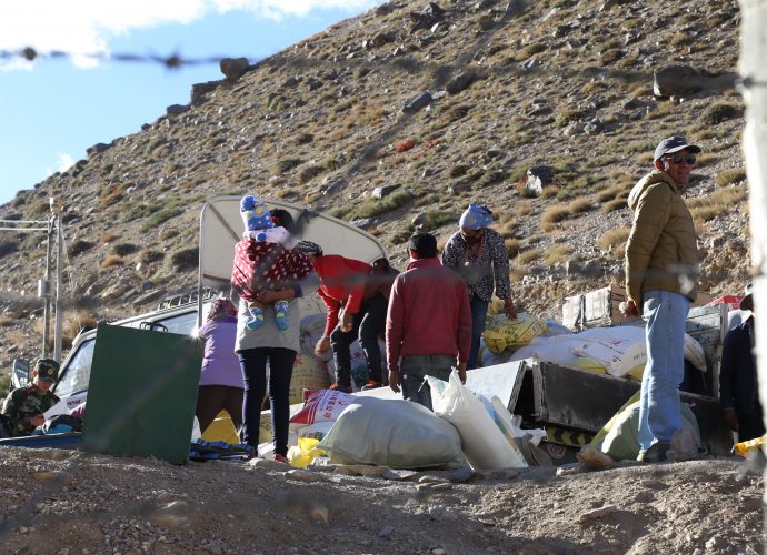 Overlooking Chinese territory, Hilsa, October 2017.
Trucks full of Chinese goods such as instant noodles, Lhasa beer, white flour, Coca-Cola, rice, and liquor were unloading when we arrived at the border. Chinese and Nepali police officers oversee the whole process, as they ritually share cigarettes as tokens of friendship. A Nepal police constable later explained that they were there to make sure that the import of alcoholic drinks does not exceed the limit in the absence of an official customs office. The border is marked by barbwire fence that runs uphill for a few dozen meters. Chinese CCTV camera, visible on the pole in the left of the frame, surveys the space beyond their border, and notice boards (not pictured) written in Tibetan and Chinese speak of the need to behave well as a matter of national pride.