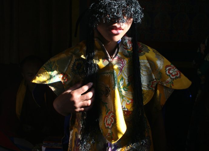 A monk enacting one of the Eight Goddesses readies himself for the ritual performance, having placed the five-corner crown (rigs lnga) on his head. The costumes are made of artificial brocade cloth in the five colors of the cardinal points, which are in accordance with the five colors of the mandala and the mendrup medicinal vessels: white, yellow, green, red, and blue. The five colors represent the five Buddha families (rgyal ba rigs lnga, see Table 1 in Sehnalova 2019), which are also symbolized by the five-pointed crown. Long black hair is affixed to the crown and covers the monk’s eyes. The hair is supposed to assemble the power of the divine realms. Its black color signifies changelessness and stability (mi ’gyur ba), since black itself cannot be changed by other colors. 