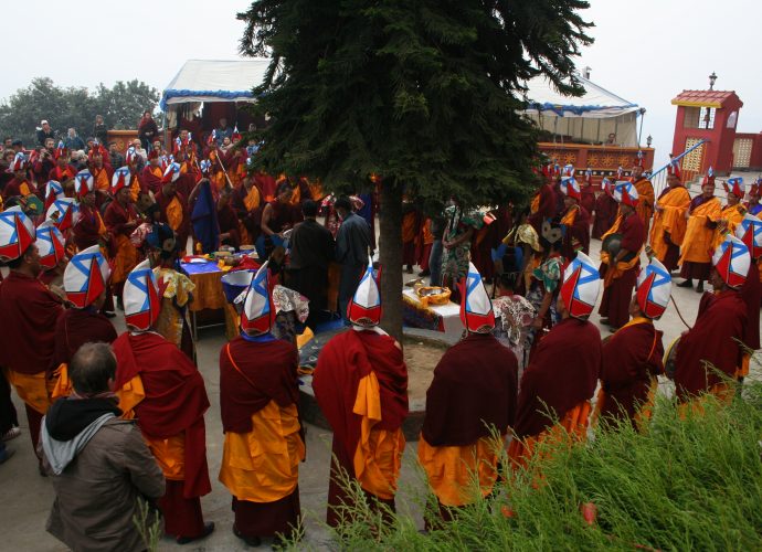 A scene from the ritual grinding of the mendrup medicine. Amchi Nyima and his main disciple Namsé (Gnam gsas, also Gnam sras) are standing in the centre (under the tree) and pour the contents of the medicinal vessels into a mortar. All members of the congregation symbolically take part in the task and beat the substances three times with a pestle. Despite the high number of participants, most of the hard work is done by Amchi Nyima and Namsé.