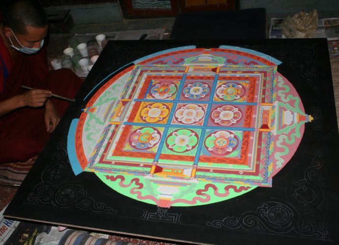 The main mendrup mandala is prepared from different types of colored sand on a wooden board. Its cardinal points with the distinctive colors are clearly visible. The mandala represents the palace of the tutelary deity Trowo Tsochok Khagying and his retinue. The nine squares stand for the distinct quarters of the divine palace and the divinities that occupy them.