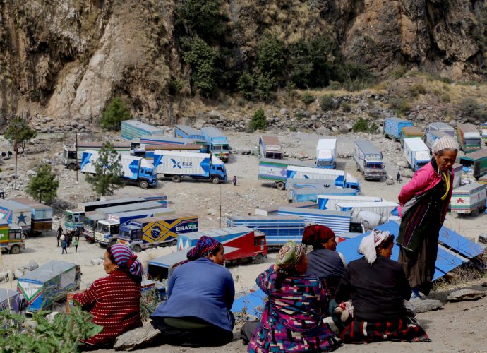 A group of local women working as porters at the border overlook a truck parking lot at Timure. A large number of local residents currently work in Timure truck park where they transport imported good after they clear customs. They are mostly from  Timure, but also include locals from neighboring villages such as Thuman, Khangjim, Bhirdim, Chilime, Gatlang, among others. There are also people from outside Rasuwa district who work as porters in Timure. According to one of our interlocutors, Timure truck park employs the greatest number of locals from the region despite the hard work it requires. Often, locals from the neighboring villages rent a small room in Timure during the peak season when it is more profitable. The majority of the people working in the park are primarily women, and toddlers can often be seen playing around as their mothers move goods.